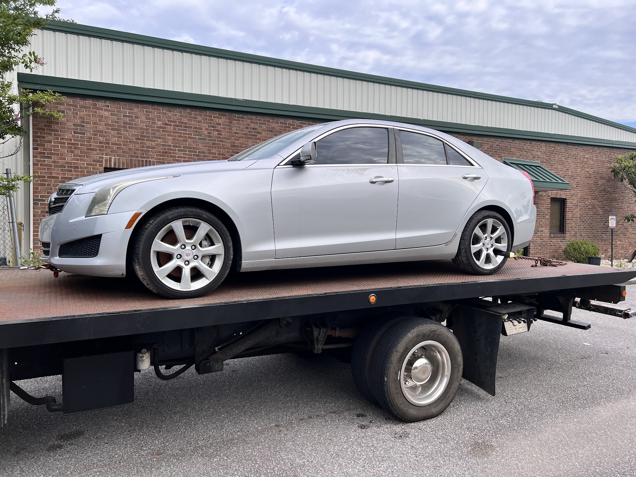A silver sedan loaded on our flatbed tow truck